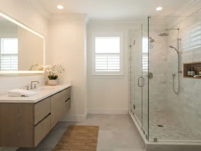 Beautifully completed small bathroom with walk-in glass shower, floating vanity, and backlit mirror